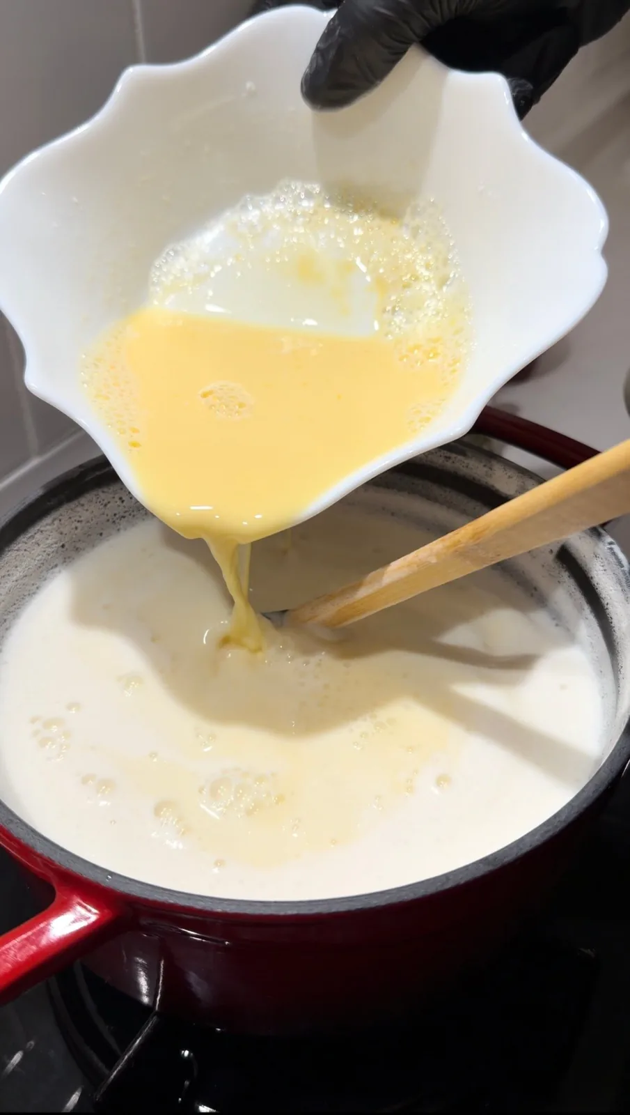 egg yolk and starch mixture being tempered with hot milk for Turkish rice pudding