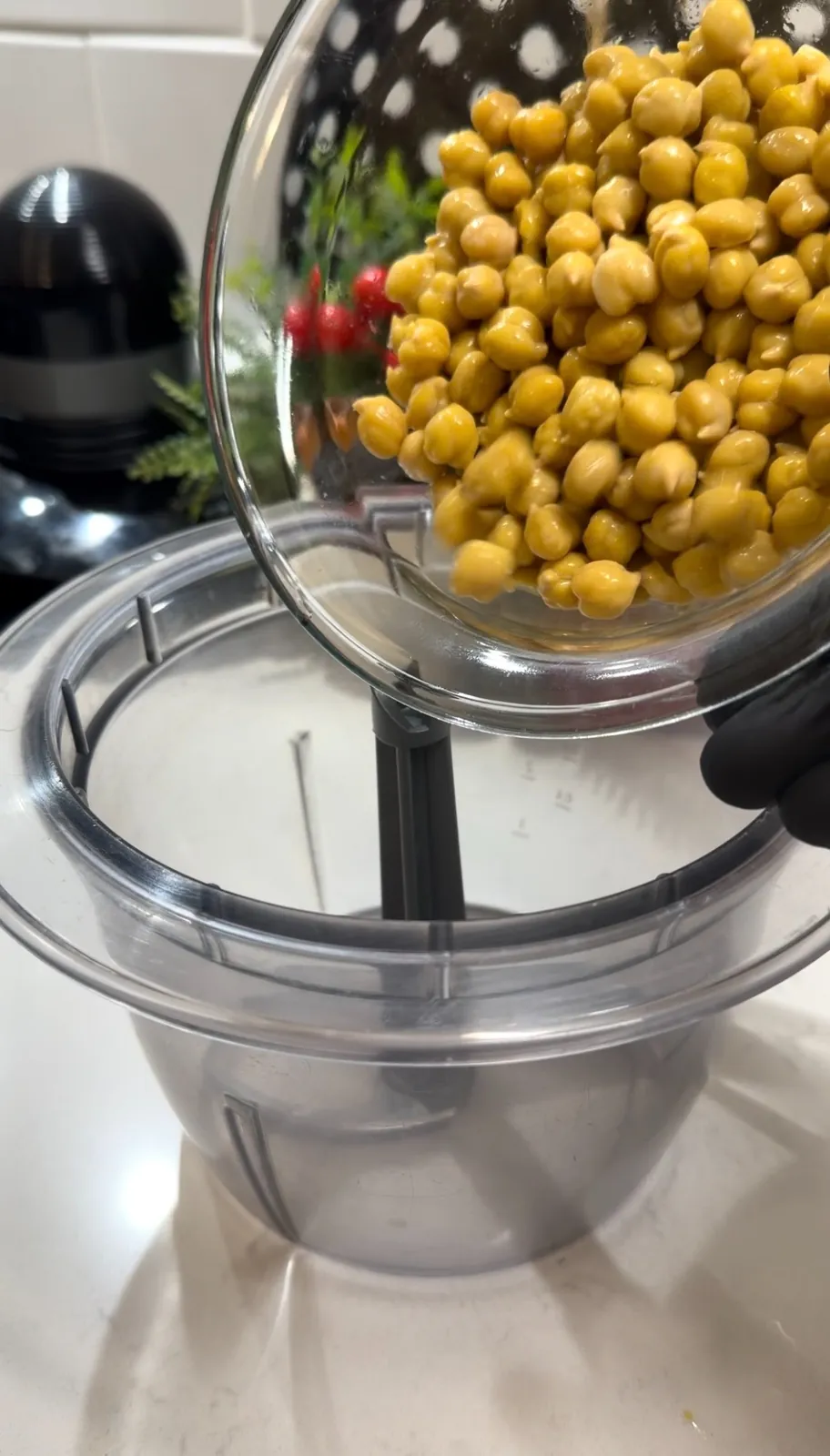 Cooked chickpeas being added to a food processor for homemade hummus