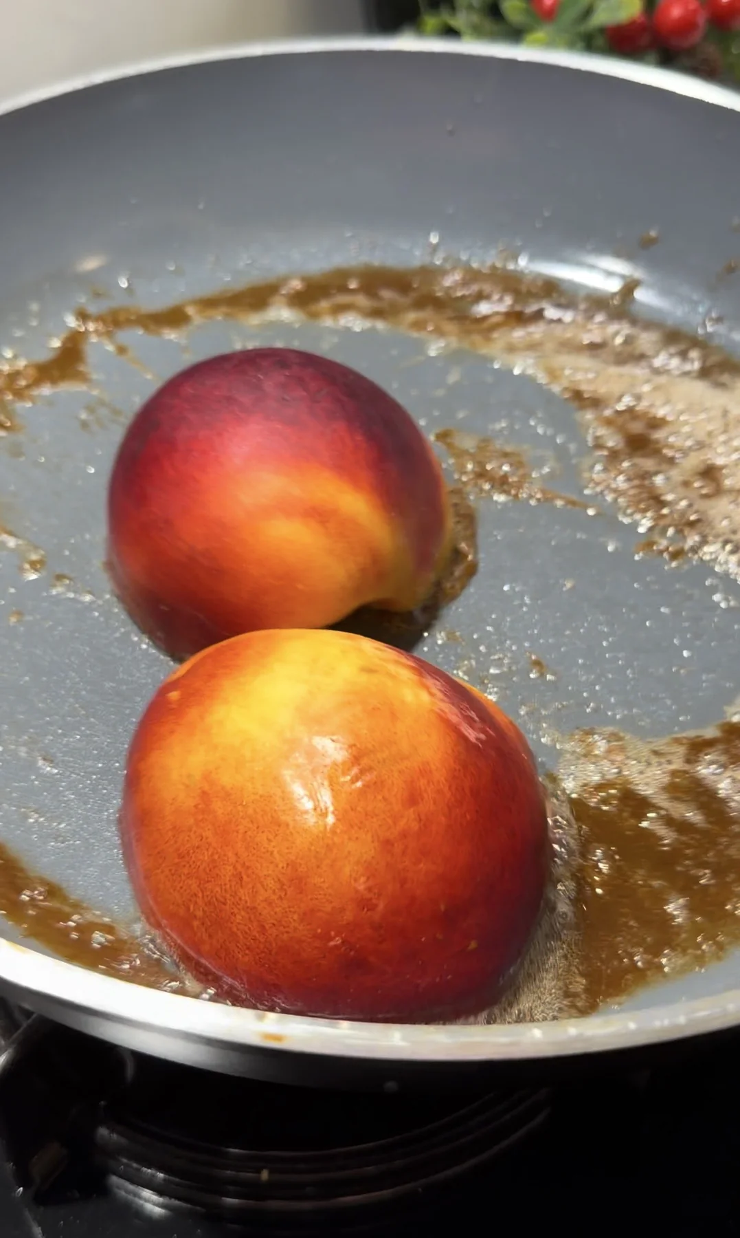 Peach halves cooking cut-side down in brown sugar caramel