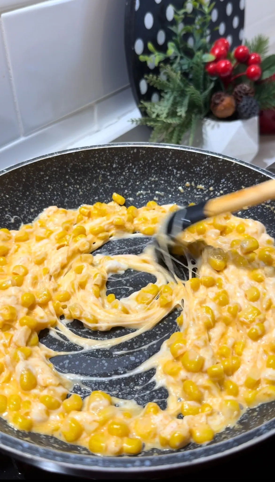 Creamy corn and melted cheese being stirred in a skillet