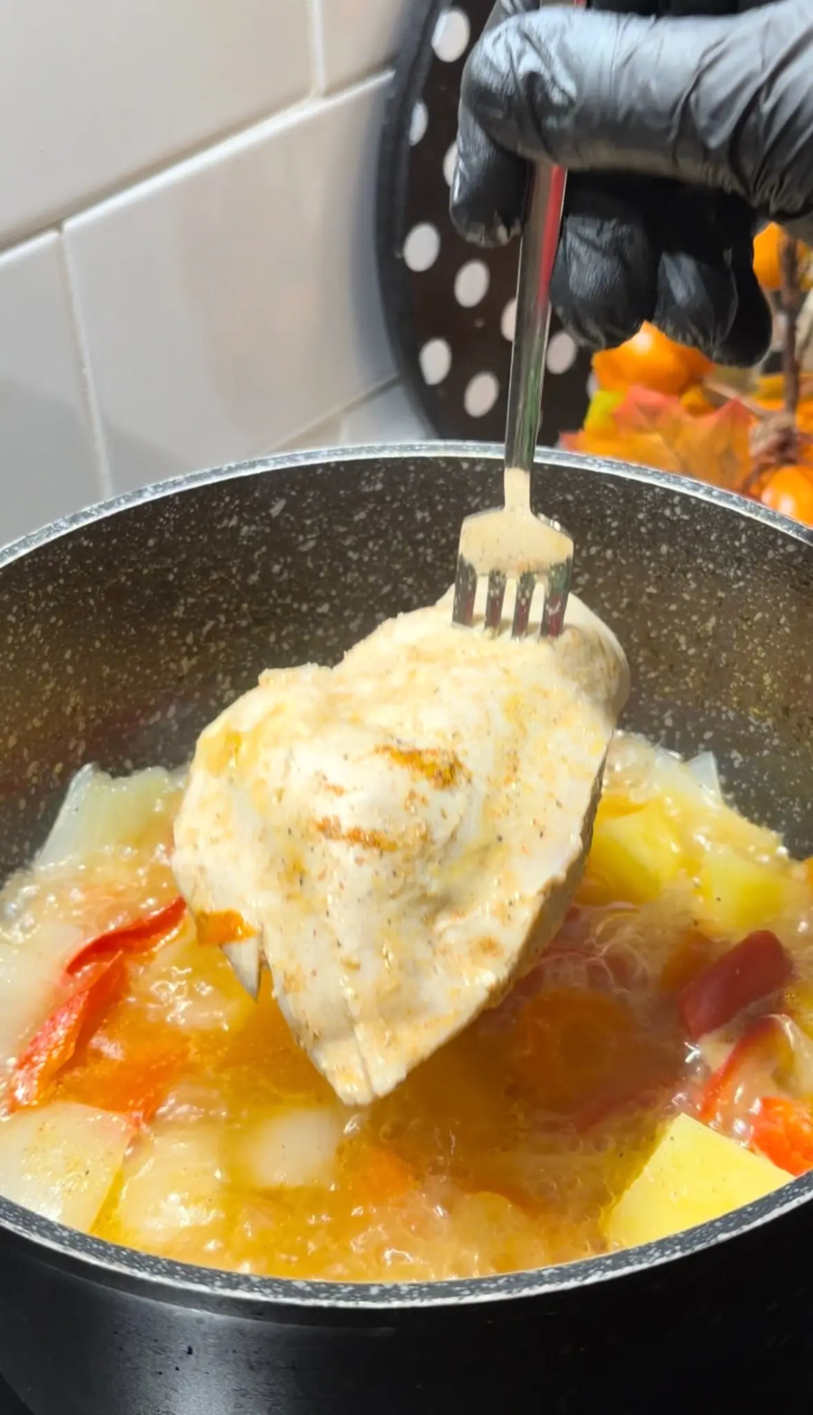 Cooked chicken breast being removed from the pot before blending the vegetables