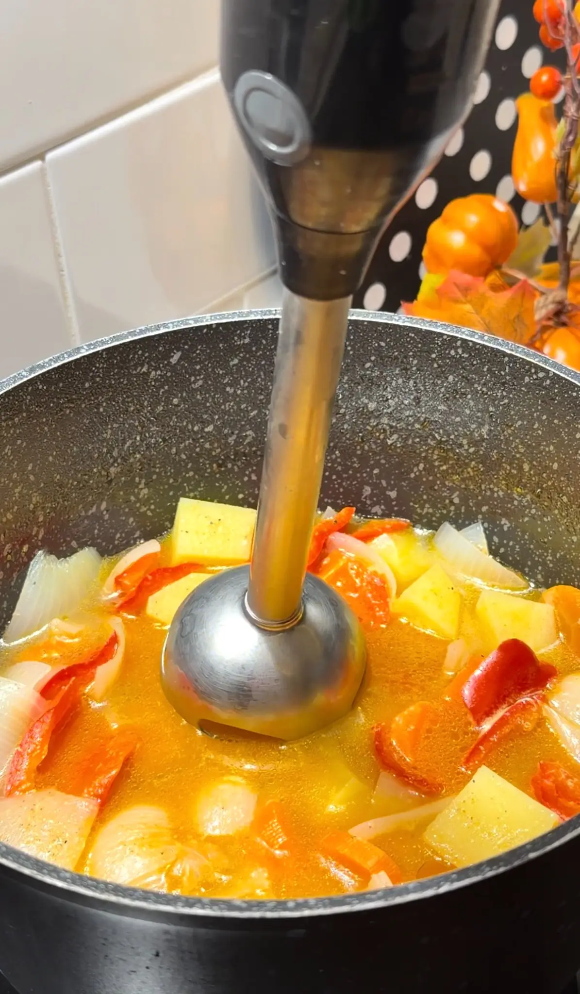 Chicken soup vegetables being blended until smooth with an immersion blender