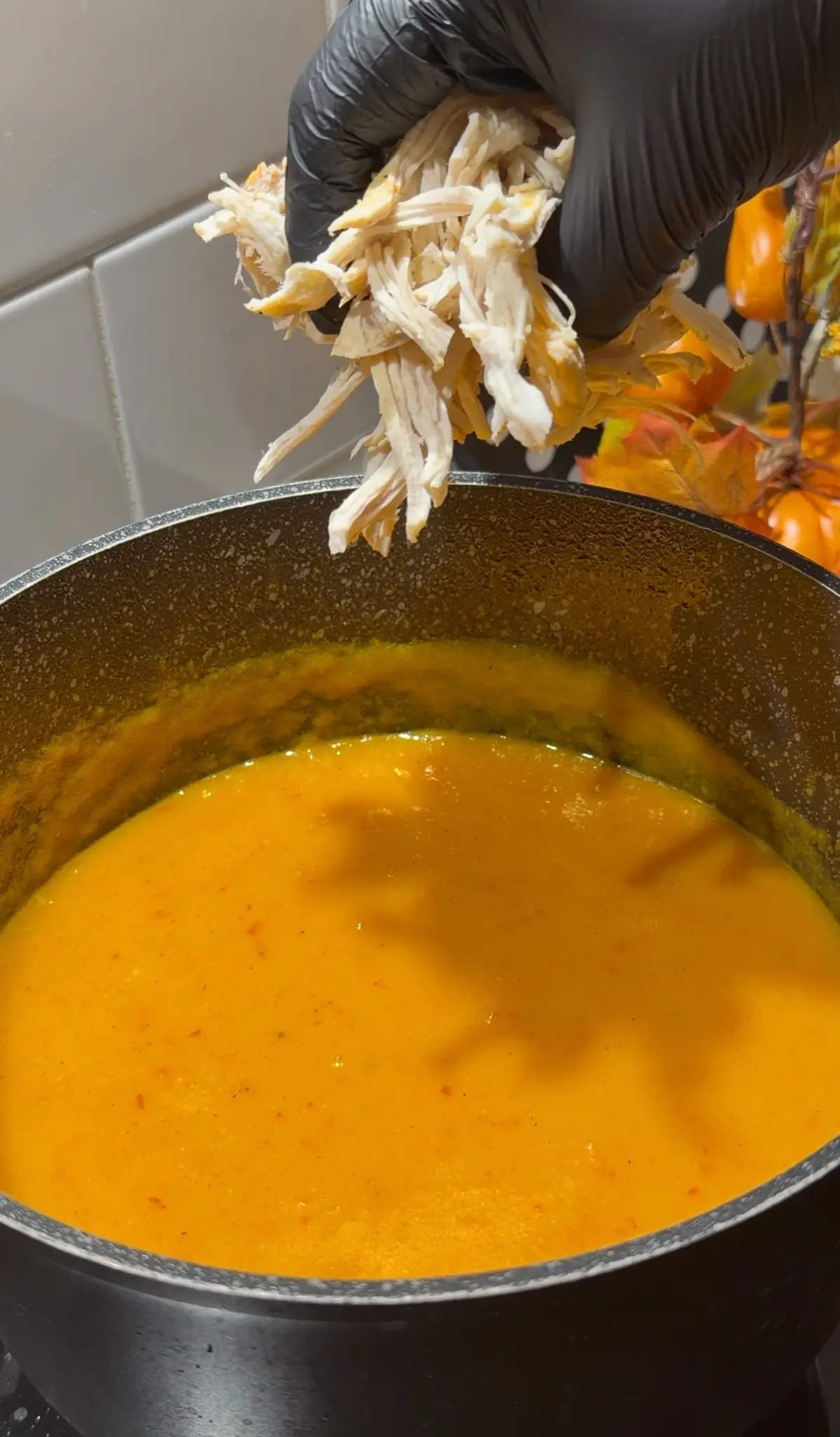 Shredded cooked chicken being added back to creamy chicken vegetable soup