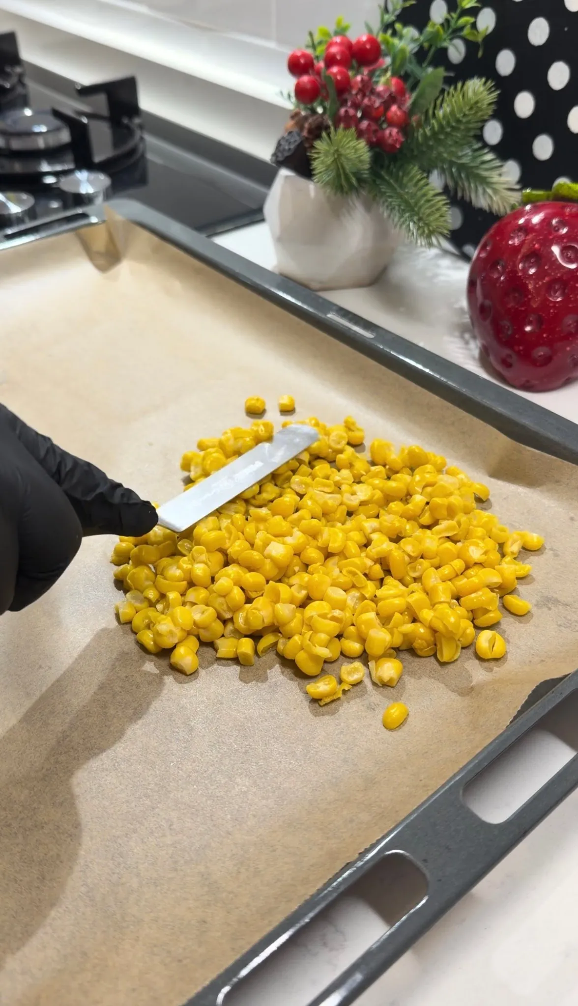Drained sweet corn being spread on a parchment-lined baking tray
