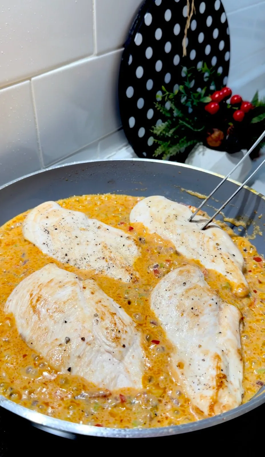 chicken breasts cooking in creamy vegetable sauce in a frying pan