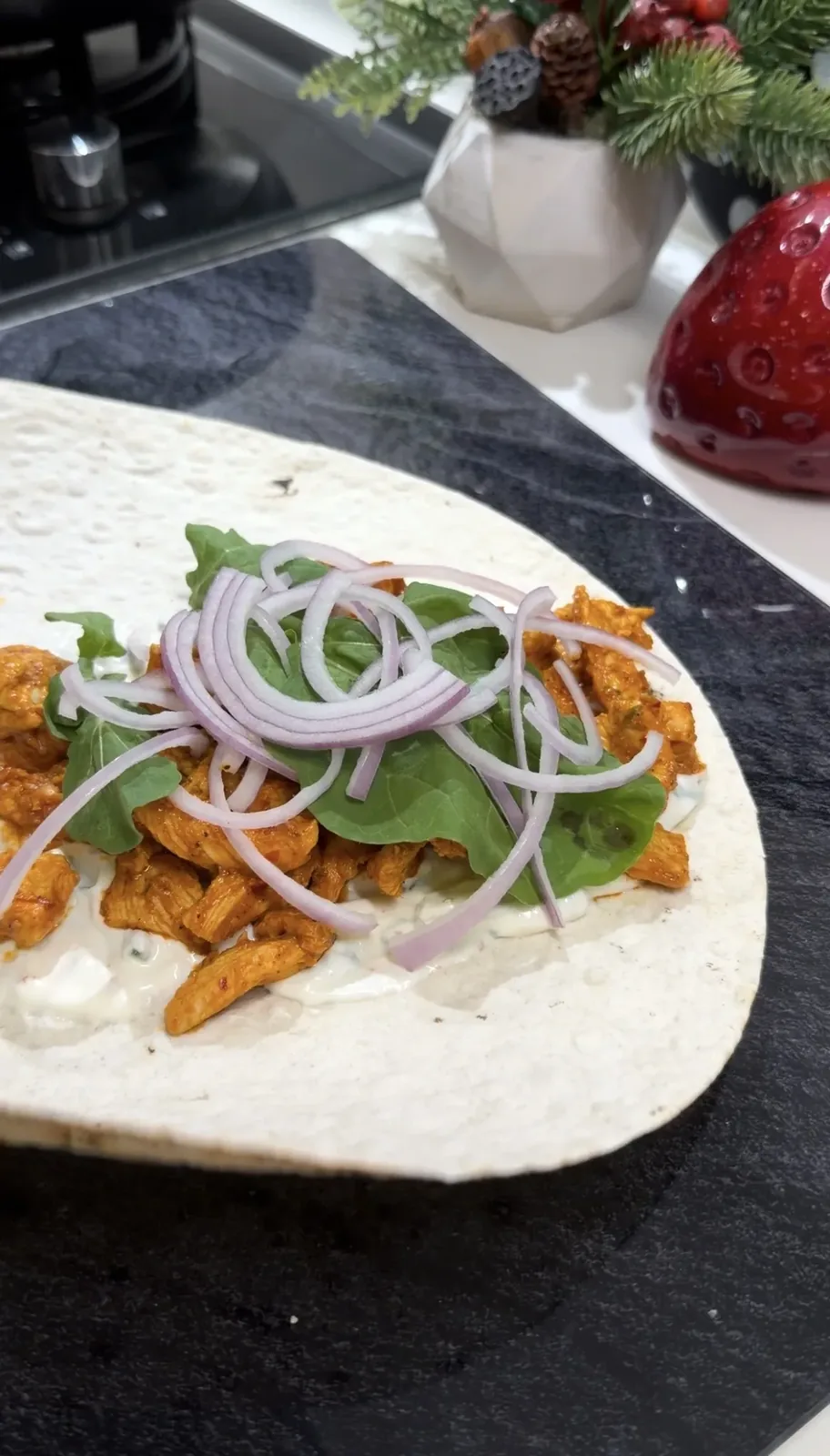 lavash topped with yogurt sauce, seasoned chicken, arugula, and sliced red onion