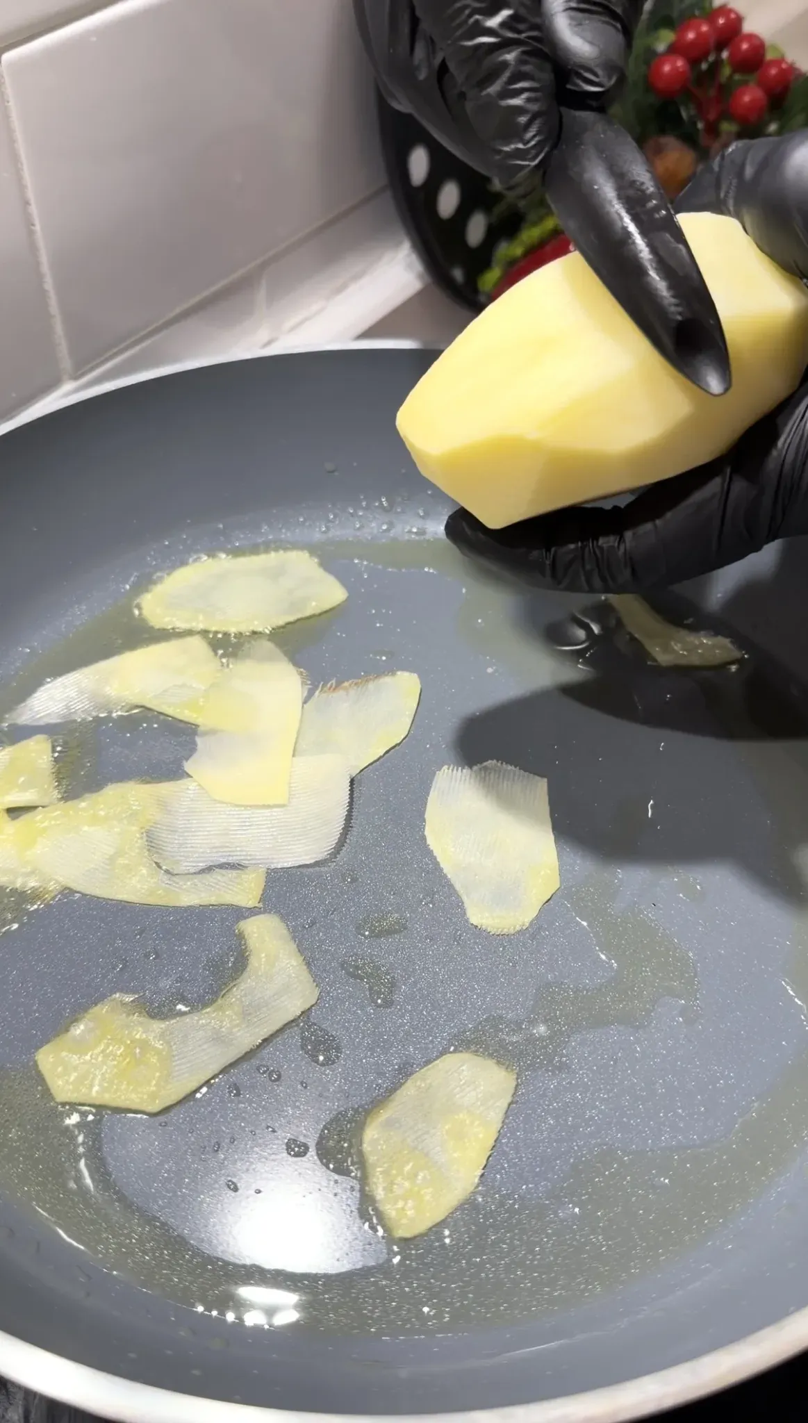 Thin potato slices being prepared in a pan for crispy potato omelet