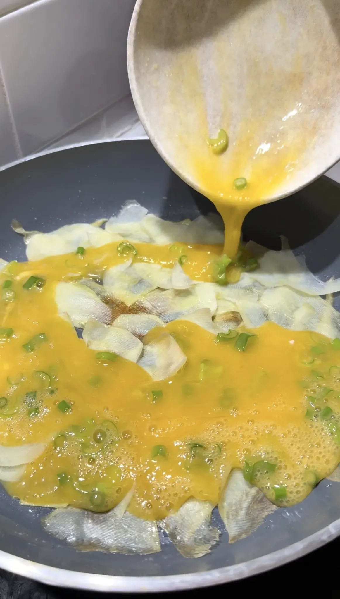 Beaten eggs with green onions poured over thin potato slices
