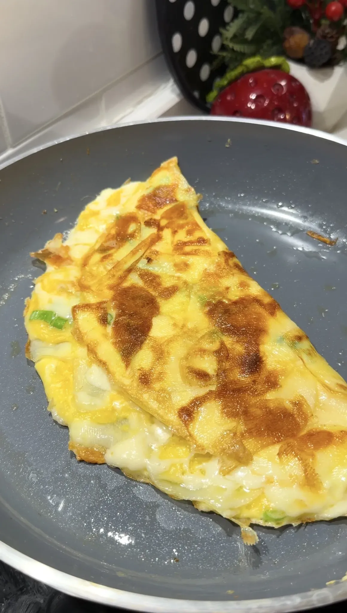 Golden crispy potato omelet folded over melted cheese in a pan