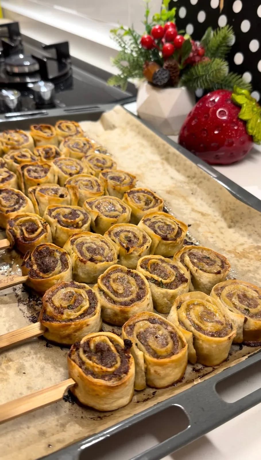 golden baked Beyti kebab rolls arranged on skewers on a baking tray