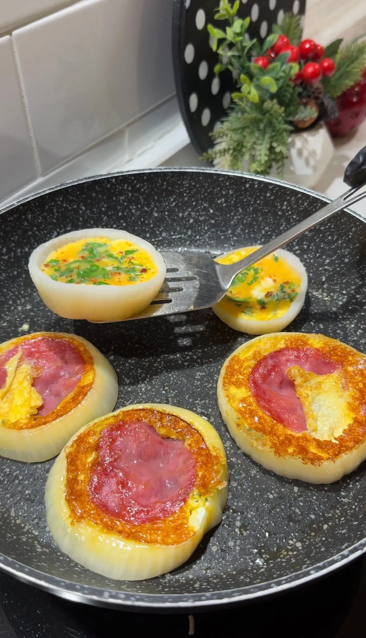 Whisked egg mixture being poured into onion rings in a skillet