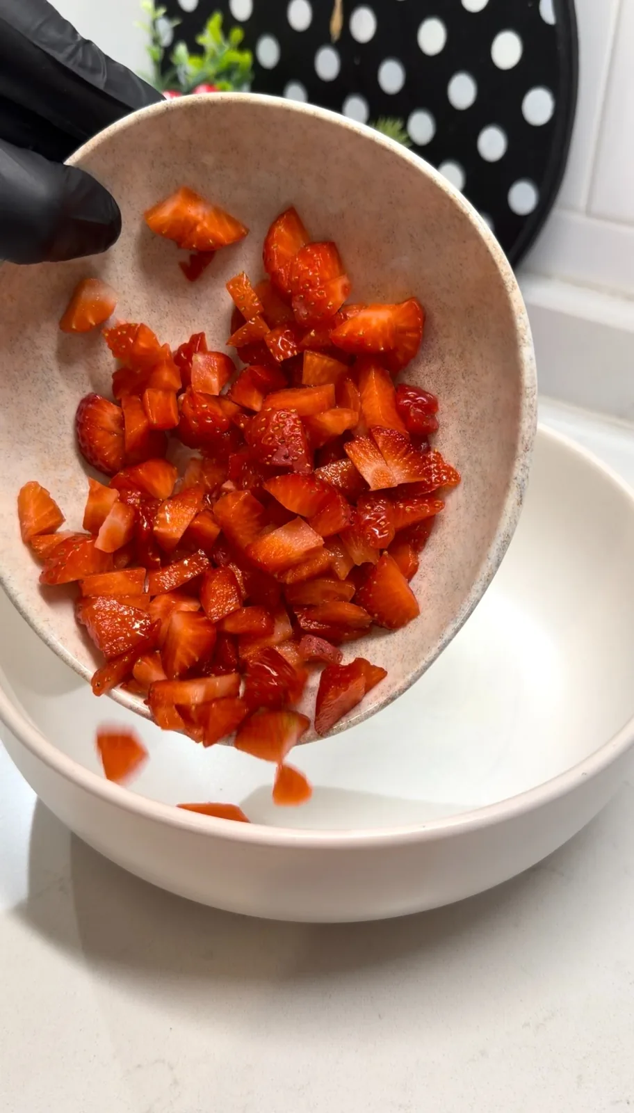 chopped fresh strawberries being added to a bowl for fruit salad