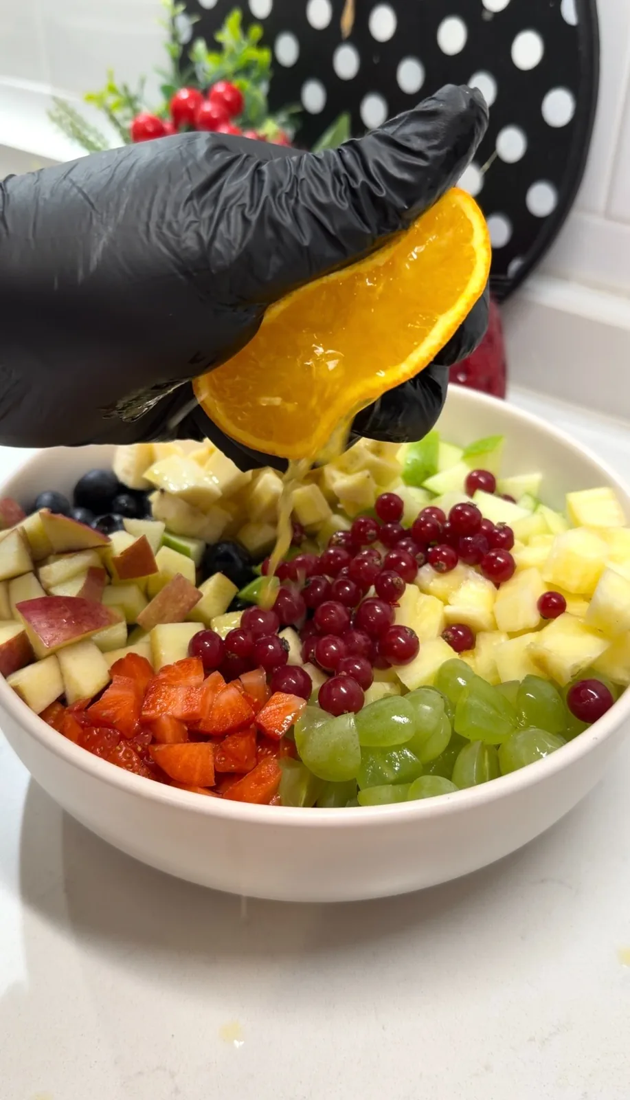 fresh orange juice being squeezed over a colorful bowl of fruit salad