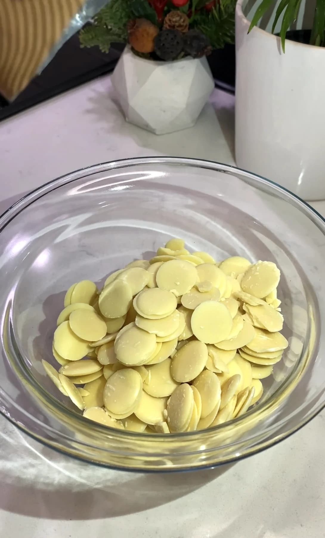 Melted white chocolate being piped over pretzel sticks to create a spider web