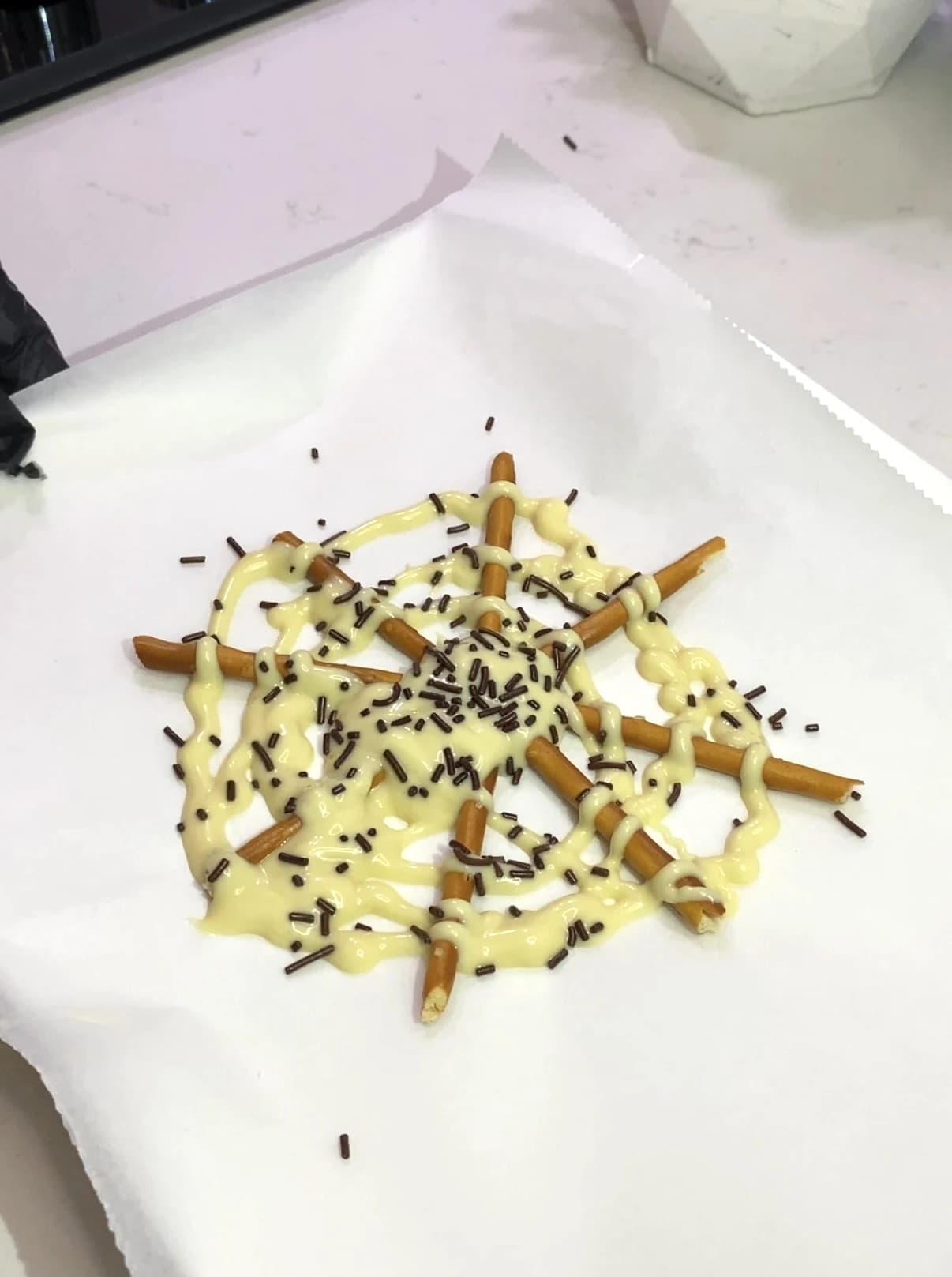 Halloween spider pretzels made with white chocolate and chocolate sprinkles
