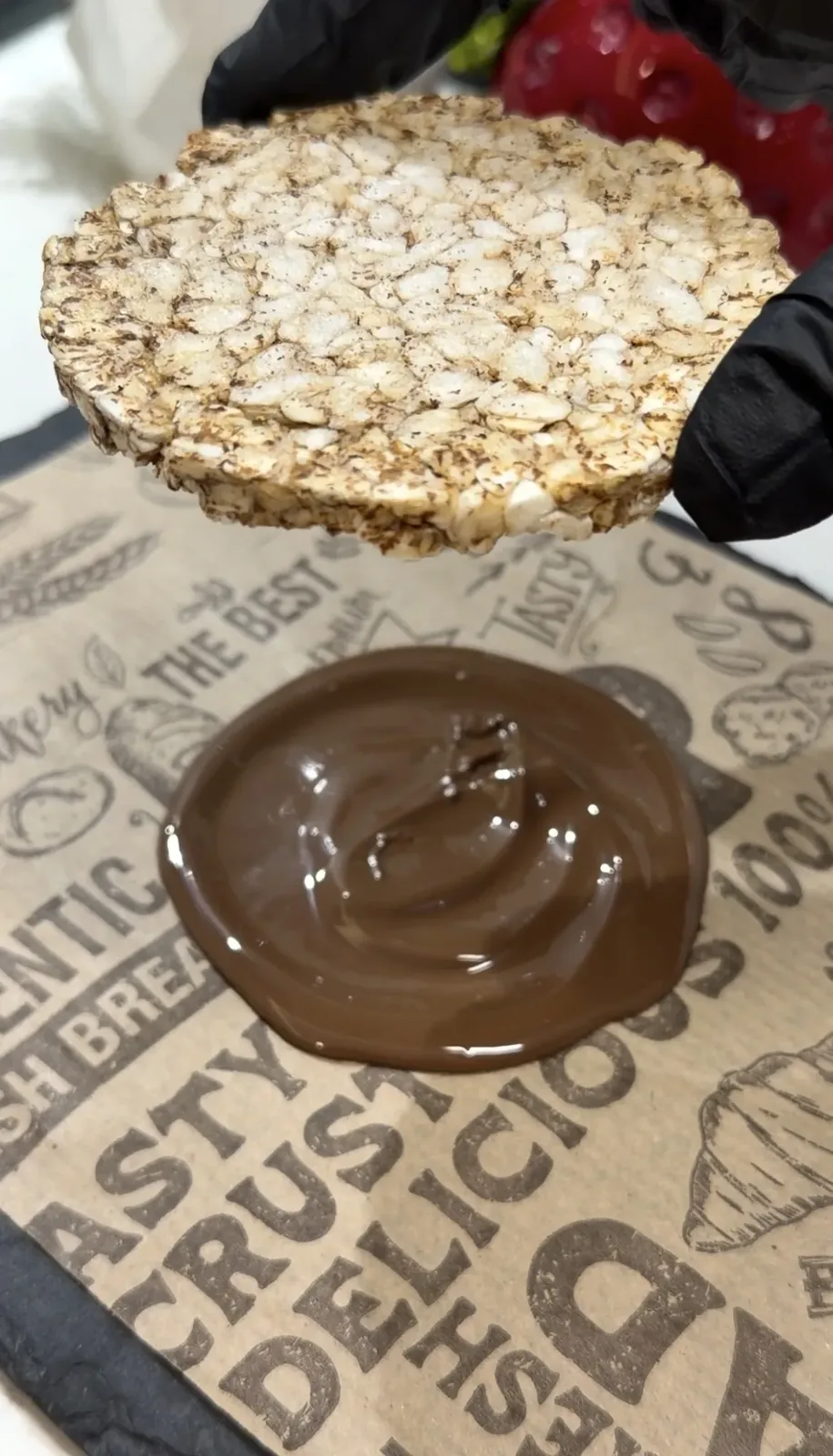 Rice cake being dipped into melted dark chocolate