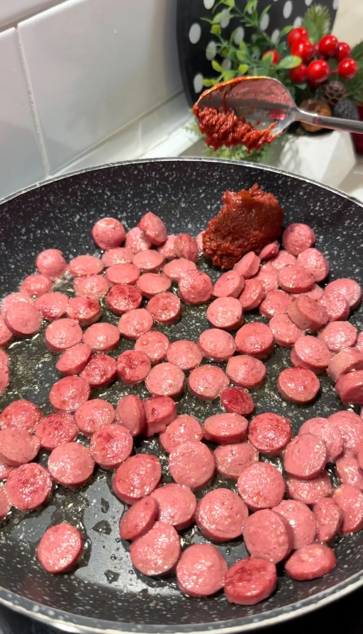 Sliced beef sausages cooking with tomato paste in a skillet