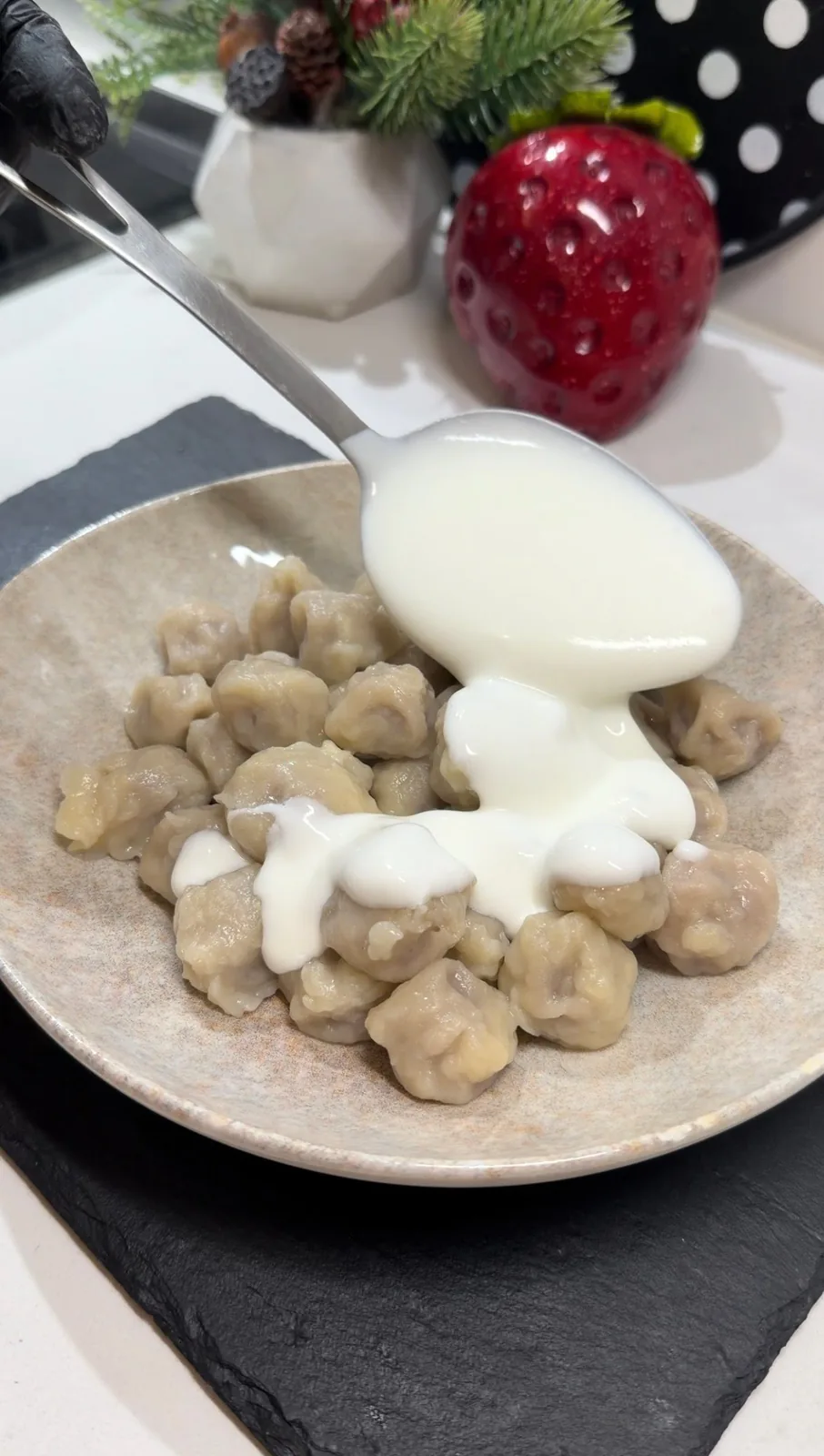 creamy yogurt being spooned over homemade lazy Turkish dumplings