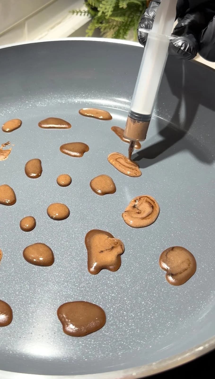Leopard spots being drawn with cocoa crepe batter in a pan