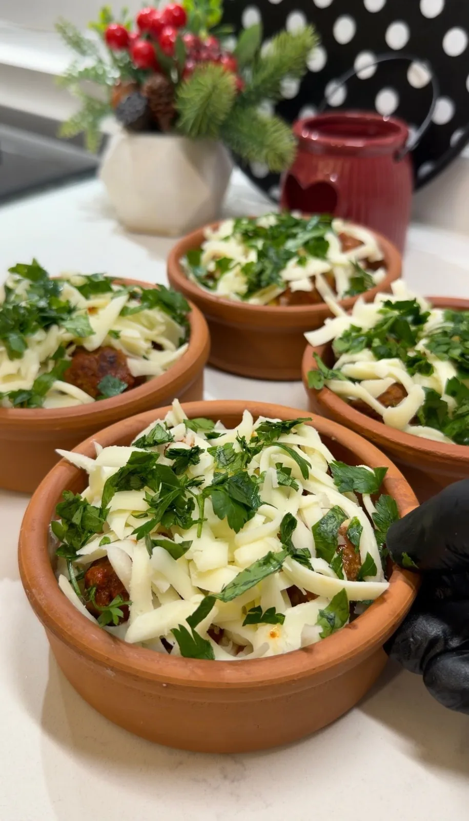 mini meatball casseroles topped with grated cheese and fresh parsley before baking