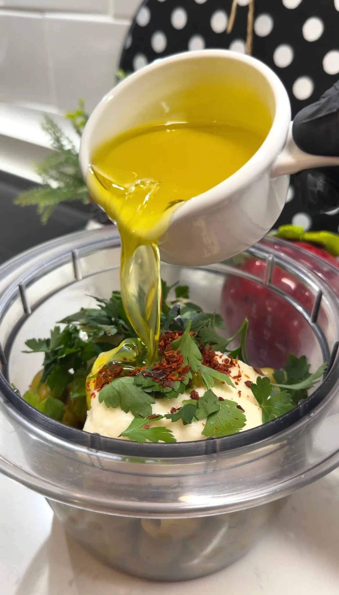 Olive oil being poured into olive and feta spread ingredients