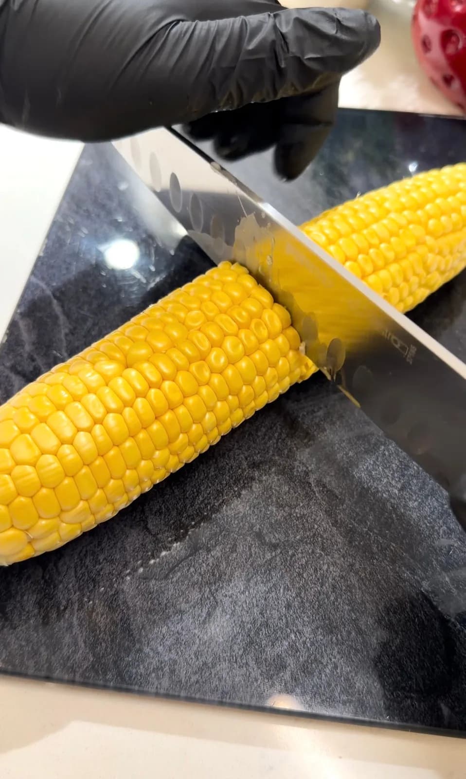Fresh corn on the cob being cut lengthwise to make corn ribs