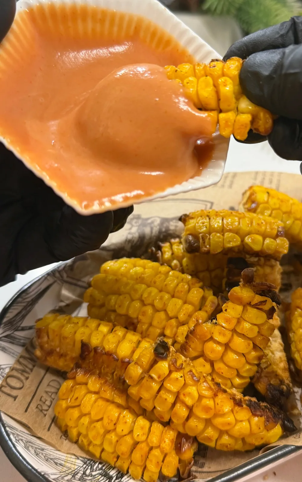 Golden oven roasted corn ribs being dipped into creamy sauce
