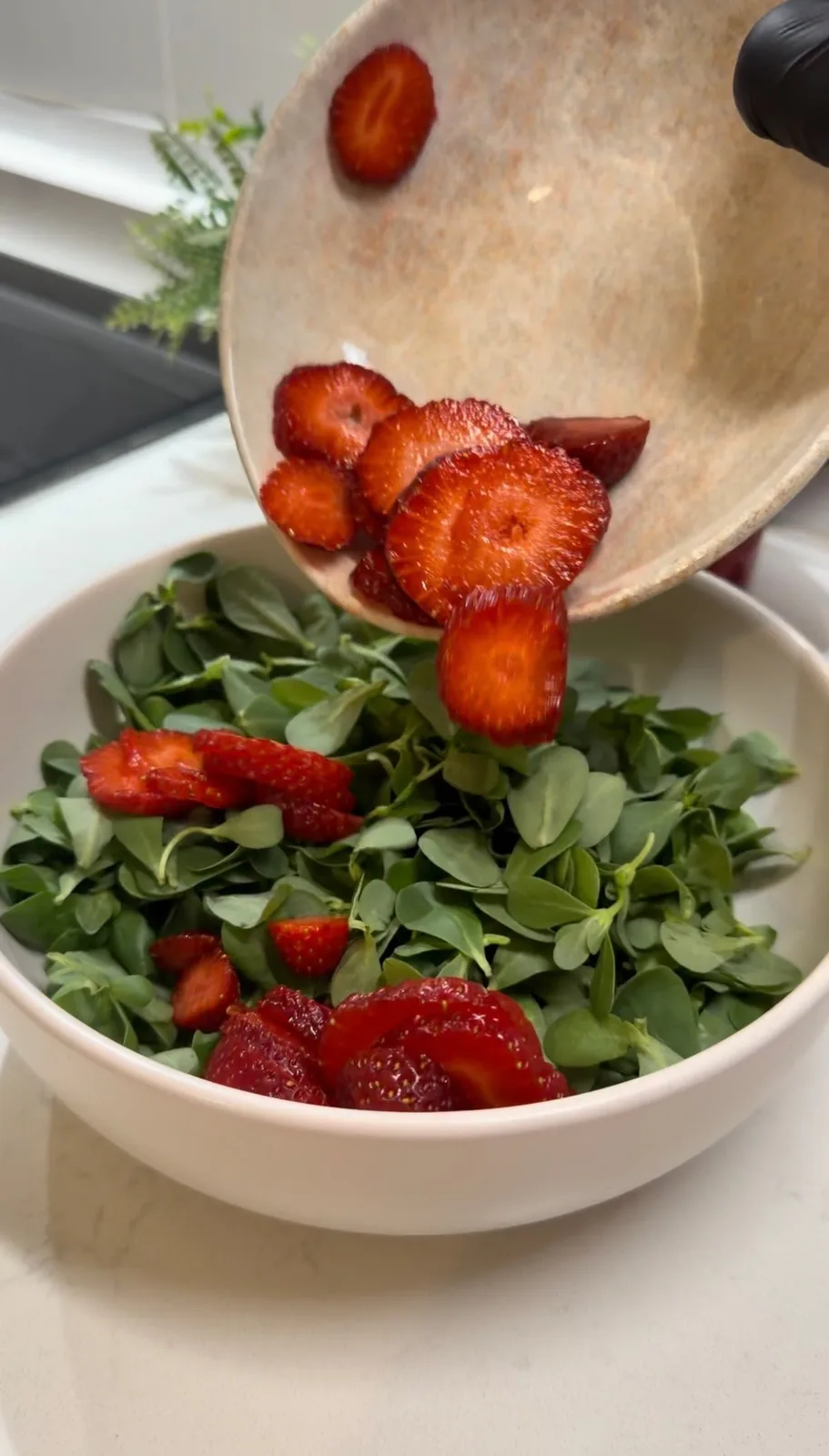 fresh sliced strawberries being added to purslane for a Mediterranean salad