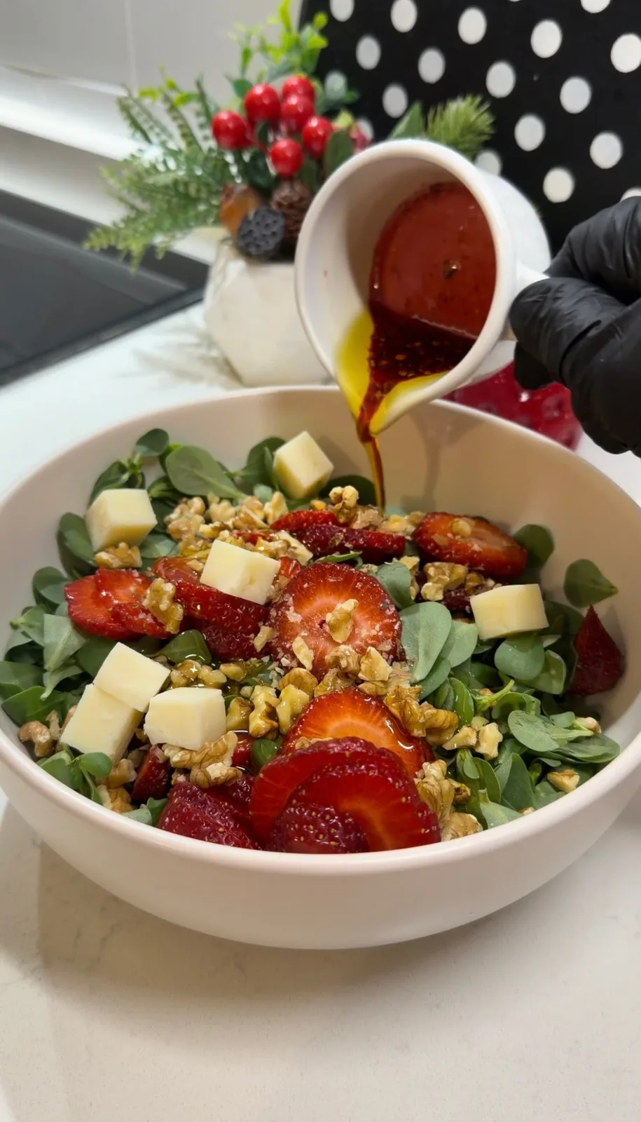 olive oil and pomegranate molasses dressing being poured over strawberry walnut purslane salad