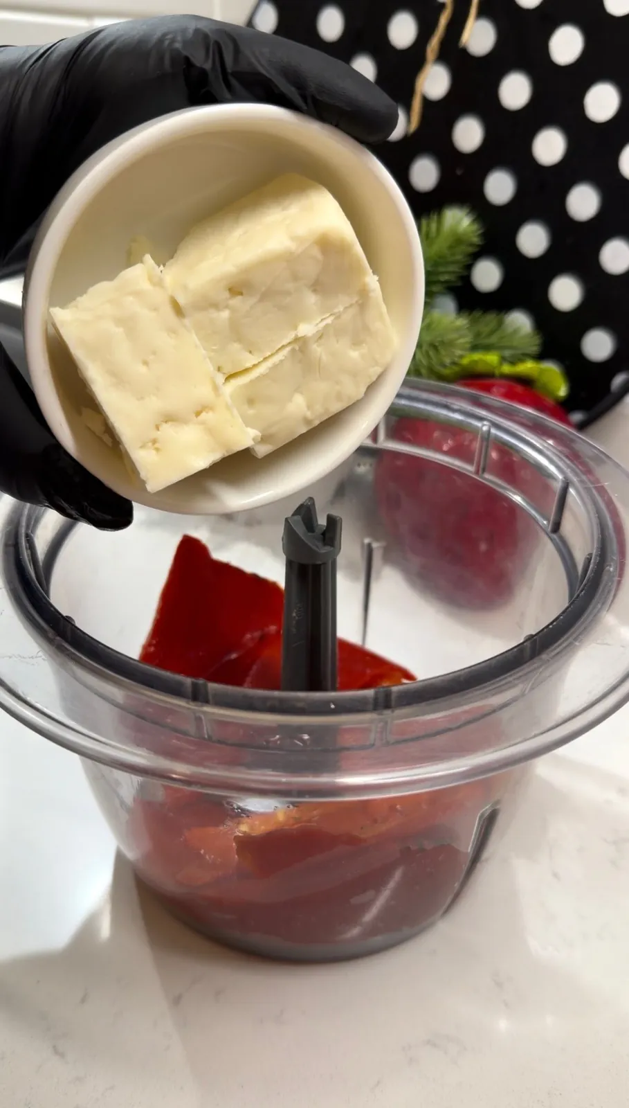 Roasted red peppers and feta cheese being added to a food processor