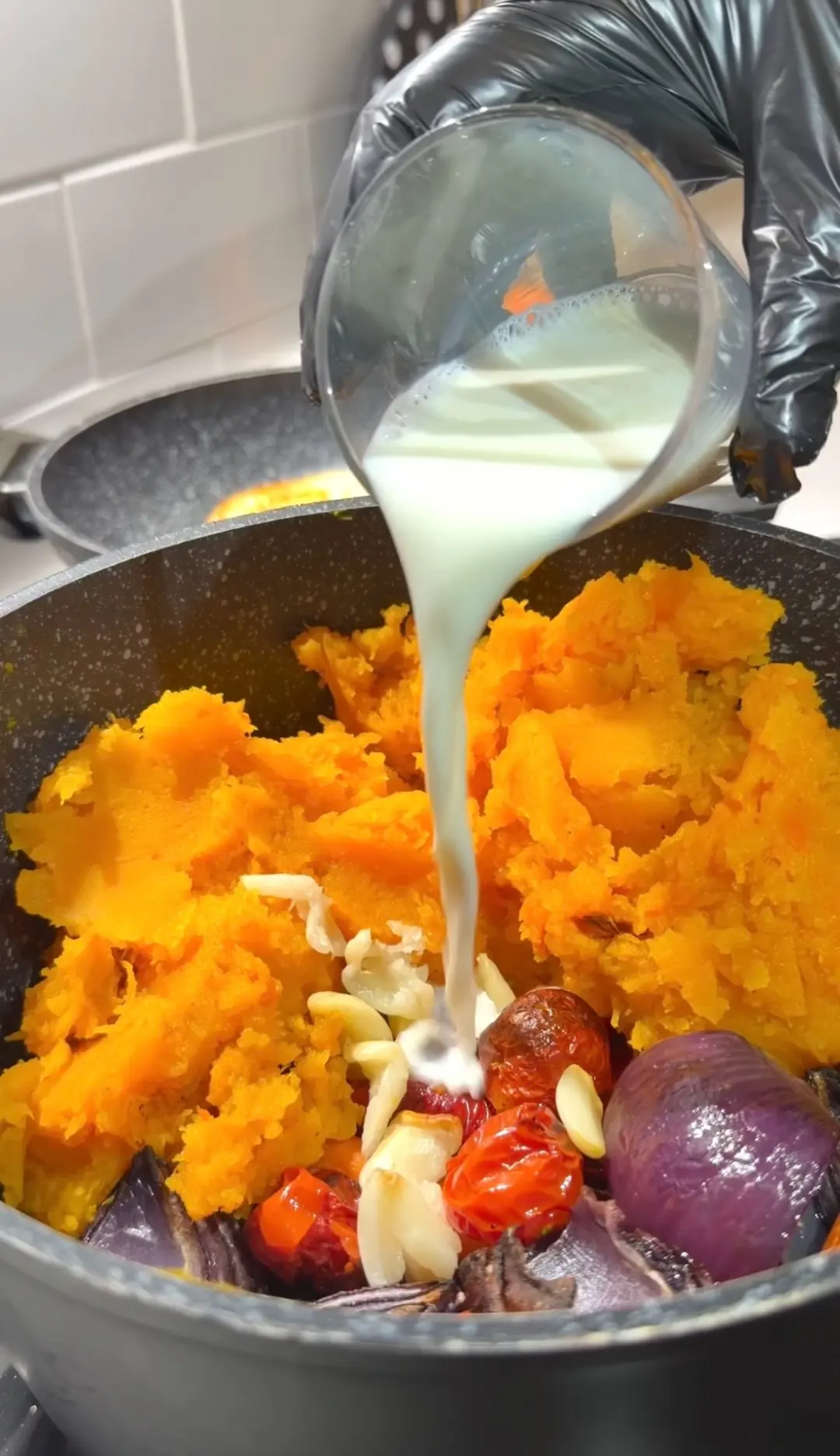 Milk being poured over roasted butternut squash and vegetables