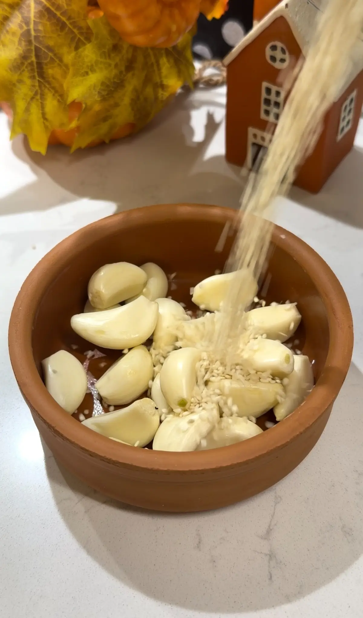 Peeled garlic cloves coated with olive oil and red pepper flakes in an ovenproof dish.