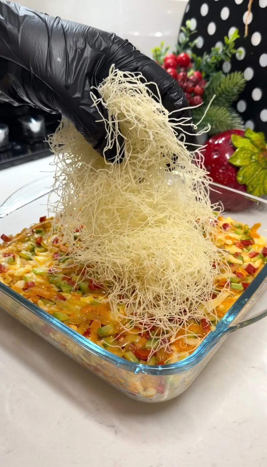 shredded kadayif pastry layered over vegetable and cheese filling in a baking dish