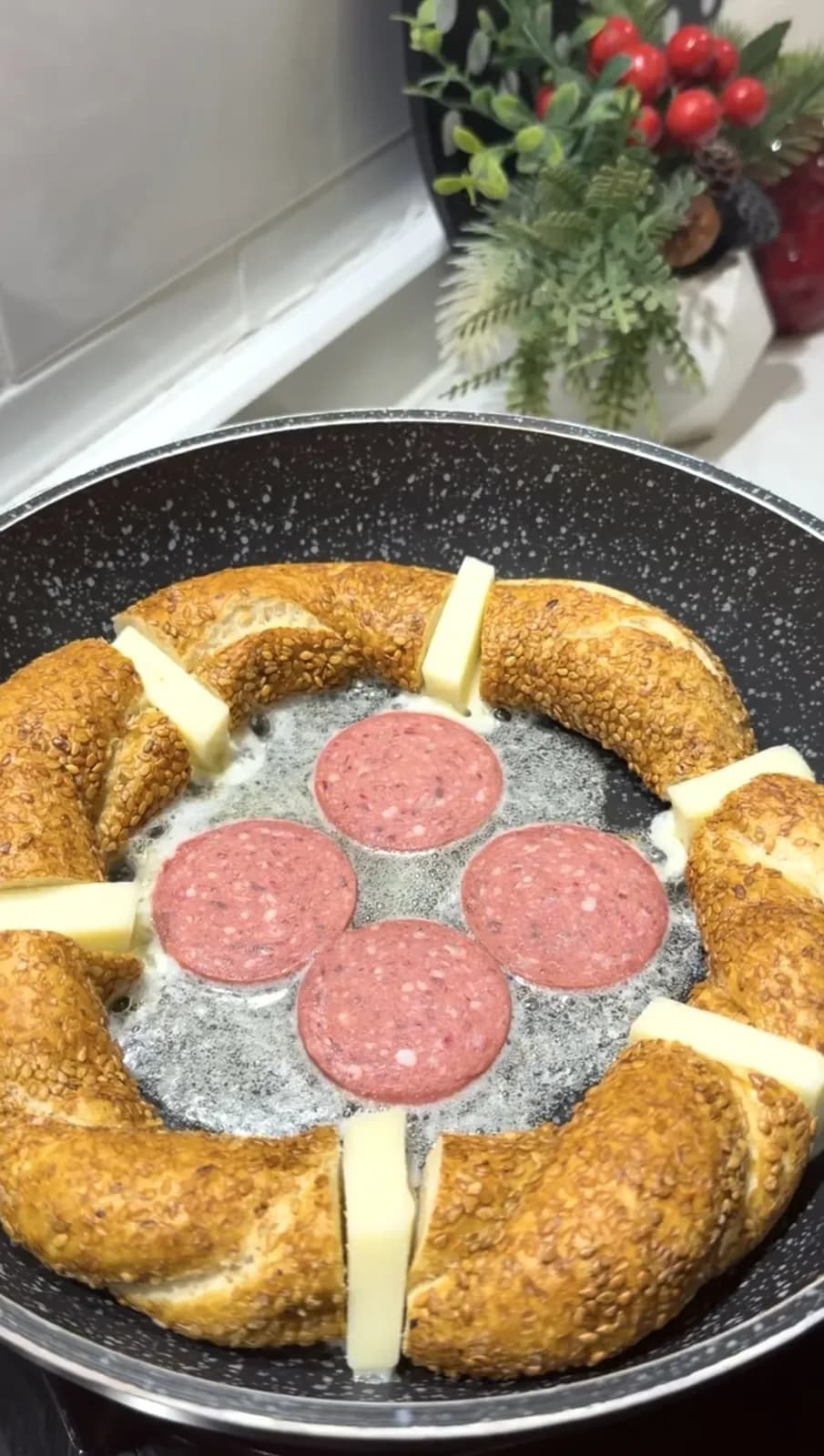 Simit pieces arranged in a pan with kashar cheese and sucuk
