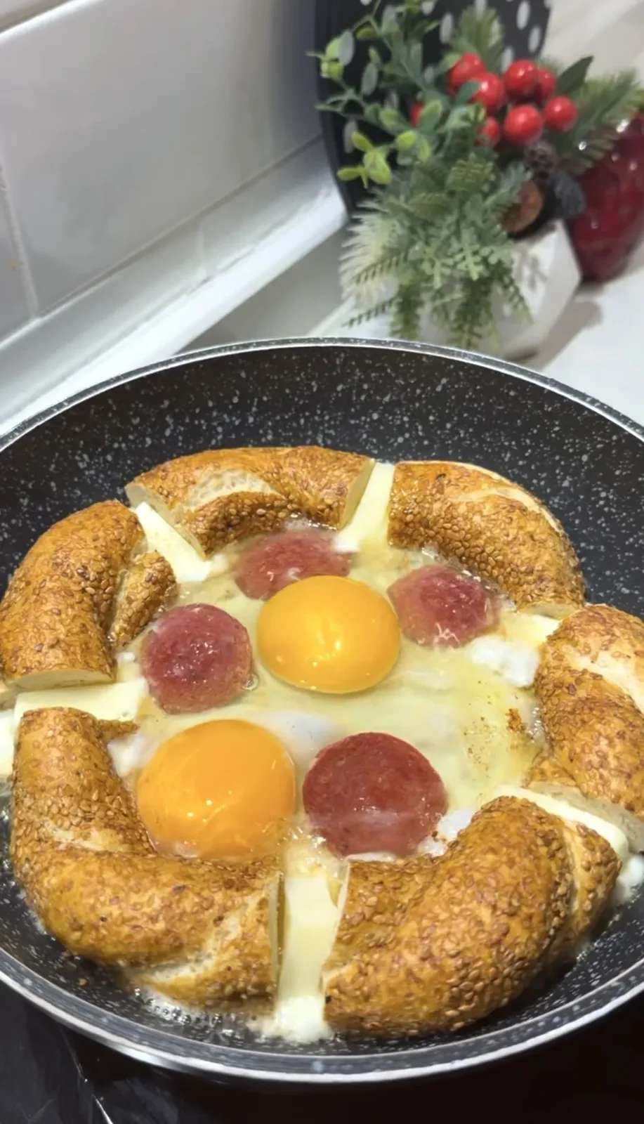 Turkish simit with eggs, sucuk and melted kashar cheese in a pan