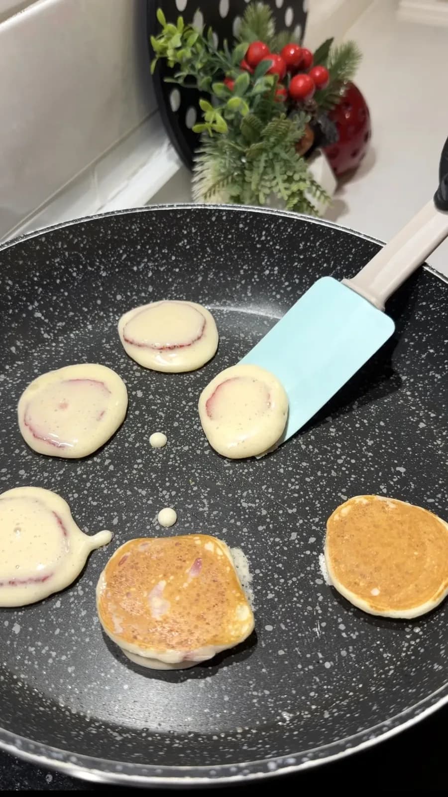 golden strawberry mini pancakes cooking in a frying pan