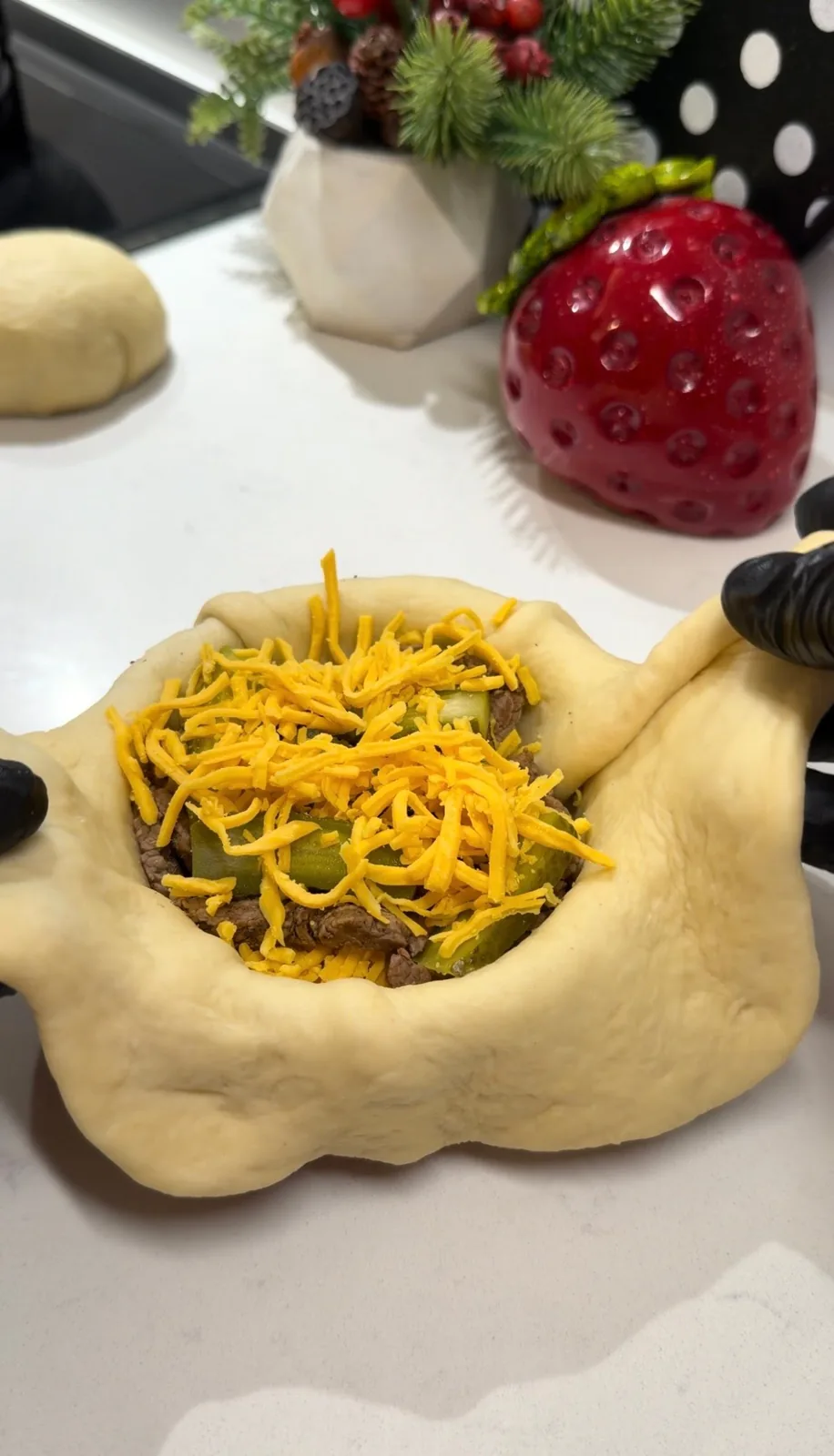 burger bun dough filled with beef, caramelized onions, pickles and grated cheddar cheese