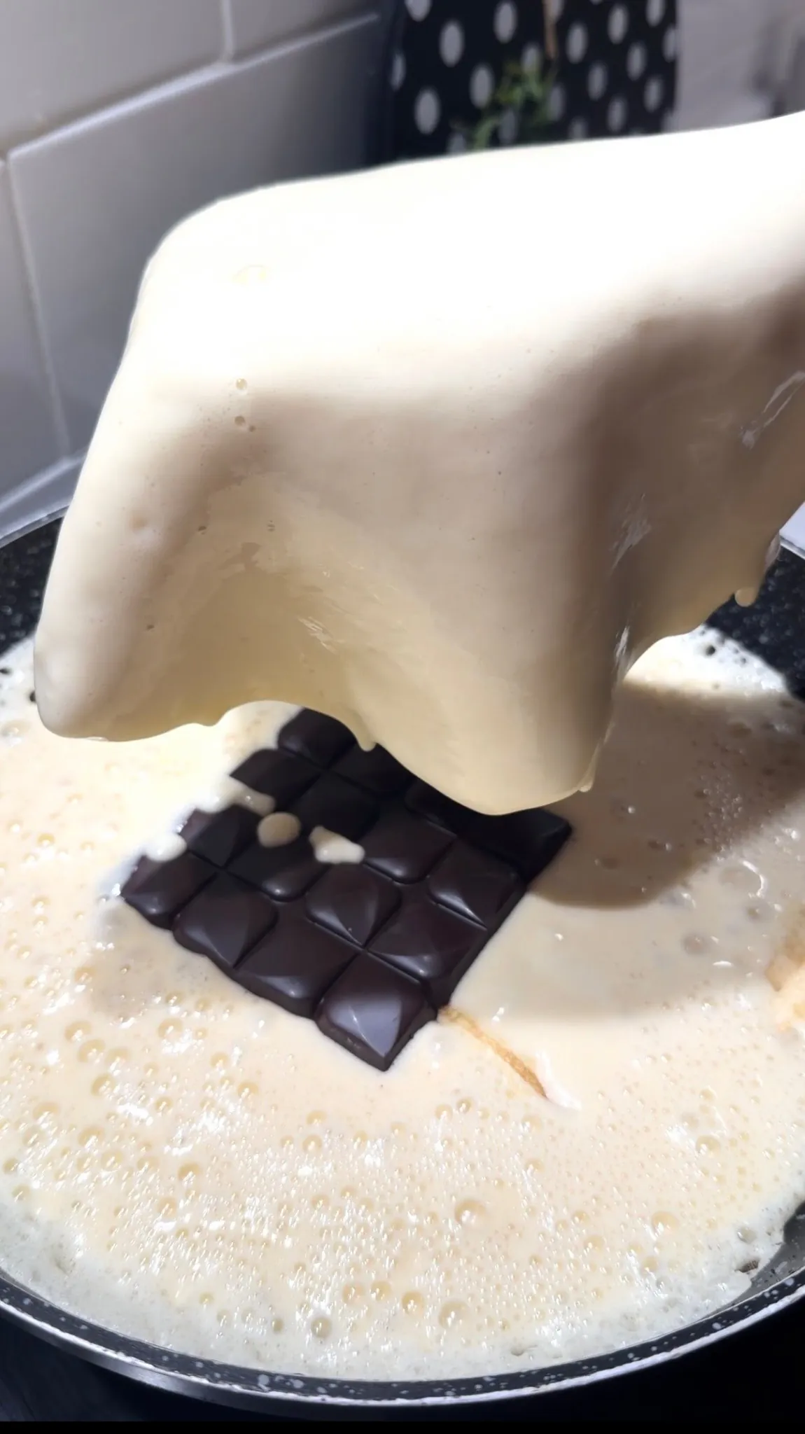 Chocolate filling being covered with pancake batter while cooking