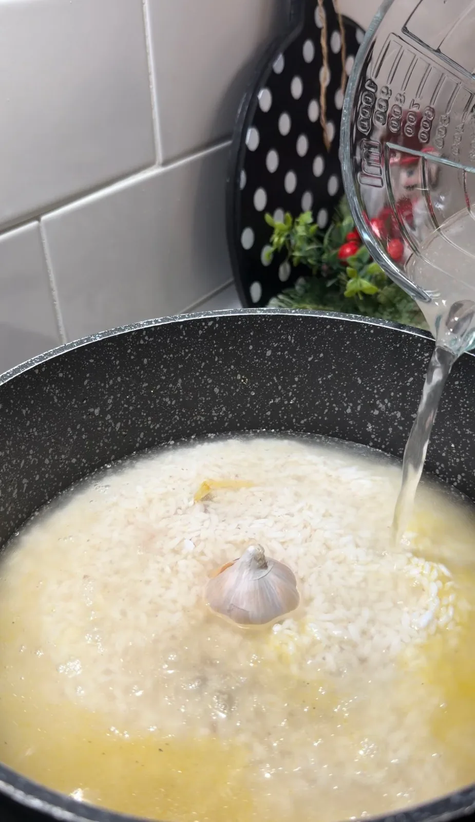 hot water being poured over rice with a whole garlic head for Uzbek pilaf