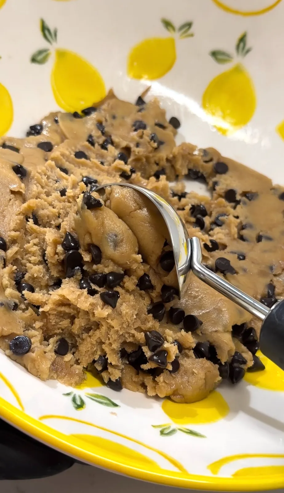 Chocolate chip cookie dough being portioned with a cookie scoop