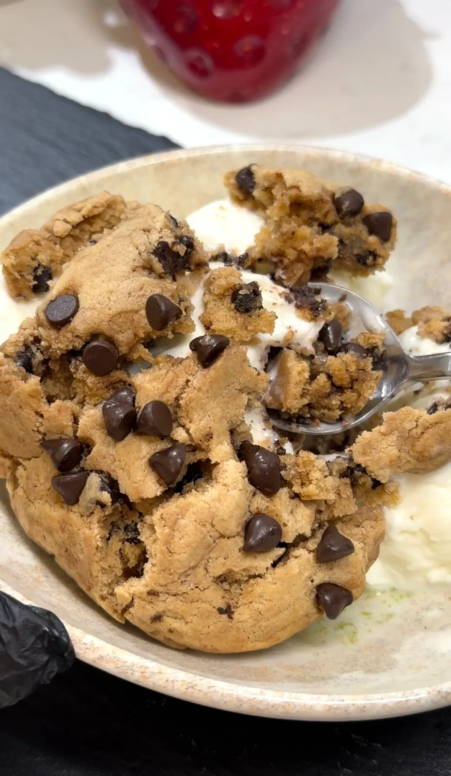 Warm chocolate chip cookies broken into pieces over melting vanilla ice cream