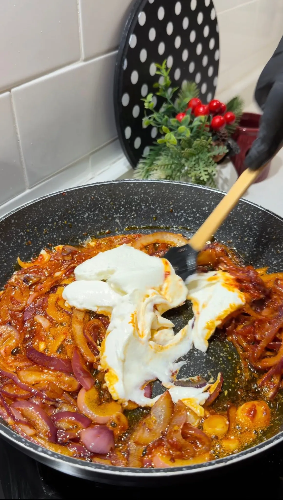 Yogurt being added to seasoned caramelized red onions